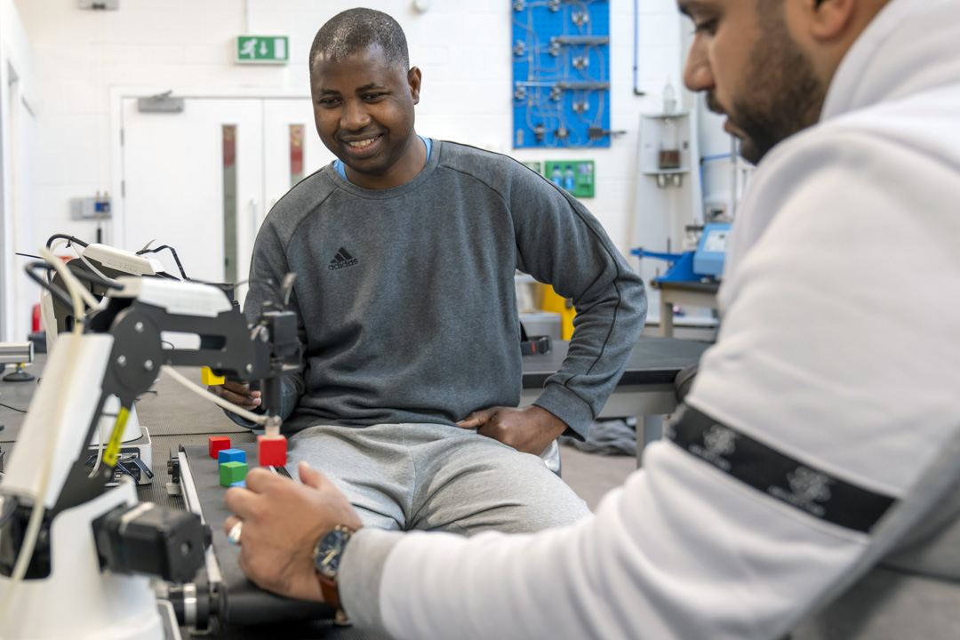 Students working with a robotic arm system during a practical electronics engineering session.