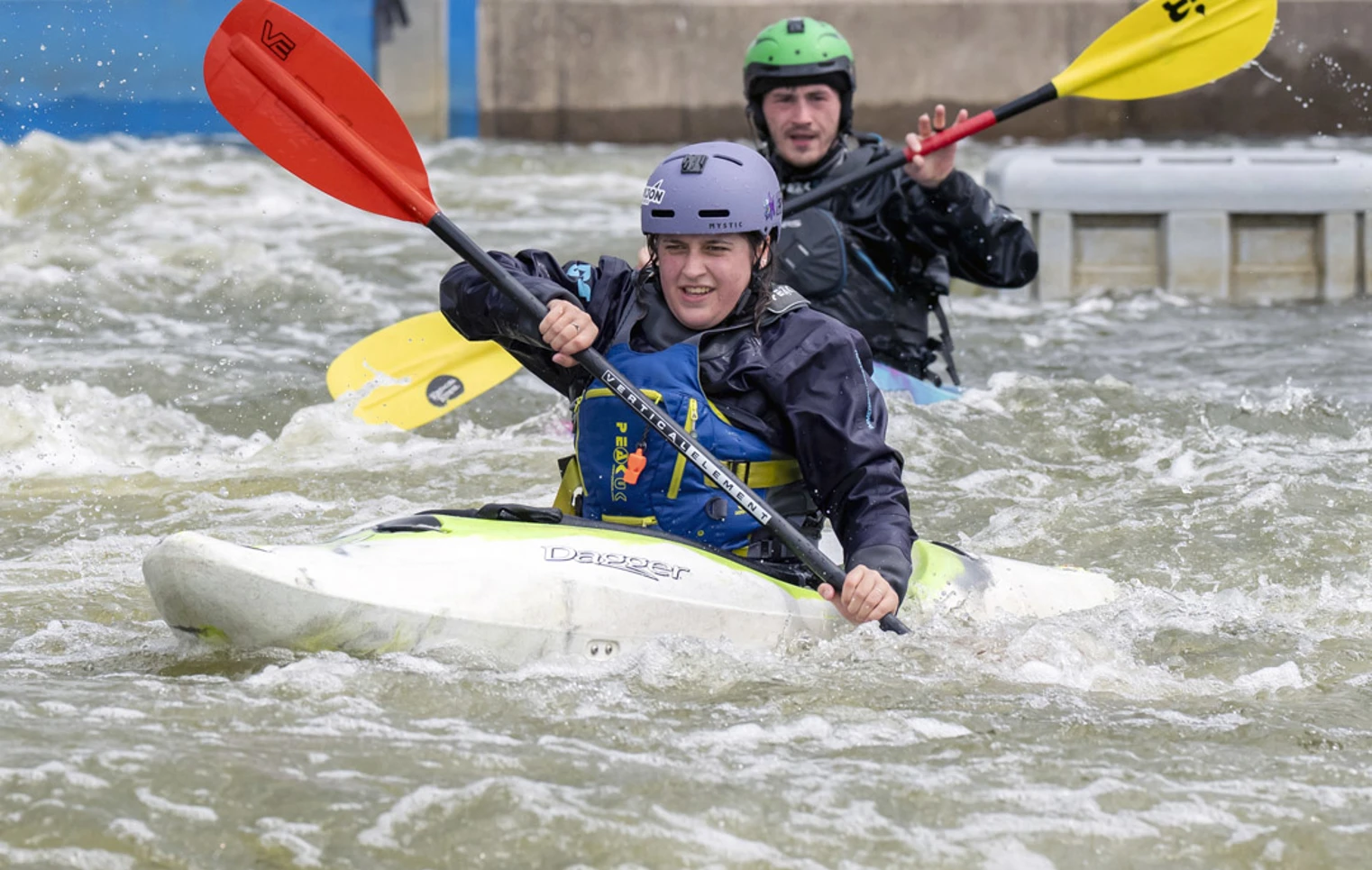 Two people kayaking in whitewater rapids, wearing helmets and waterproof gear during an outdoor activity session. Two people kayaking in whitewater rapids, wearing helmets and waterproof gear during an outdoor activity session.