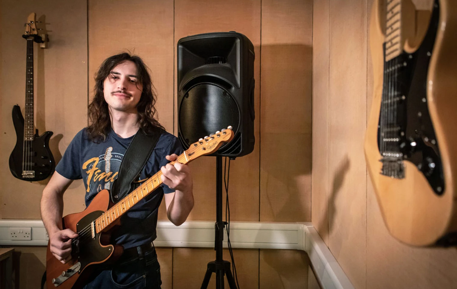 A guitarist wearing a Fender t-shirt playing an electric guitar. A guitarist wearing a Fender t-shirt playing an electric guitar.