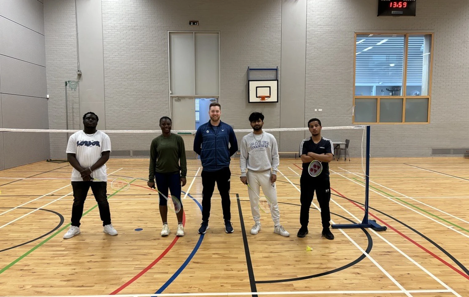 Group of students and a coach posing in the gym hall at Glasgow Kelvin College after a badminton session, standing on either side of the net. Group of students and a coach posing in the gym hall at Glasgow Kelvin College after a badminton session, standing on either side of the net.