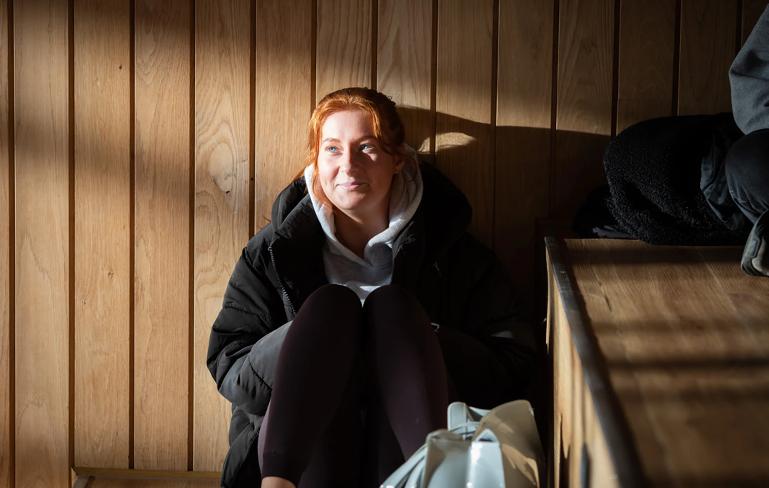Student sitting in sunlight on wooden steps at Glasgow Kelvin College Springburn campus, wearing casual clothes and smiling softly Student sitting in sunlight on wooden steps at Glasgow Kelvin College Springburn campus, wearing casual clothes and smiling softly