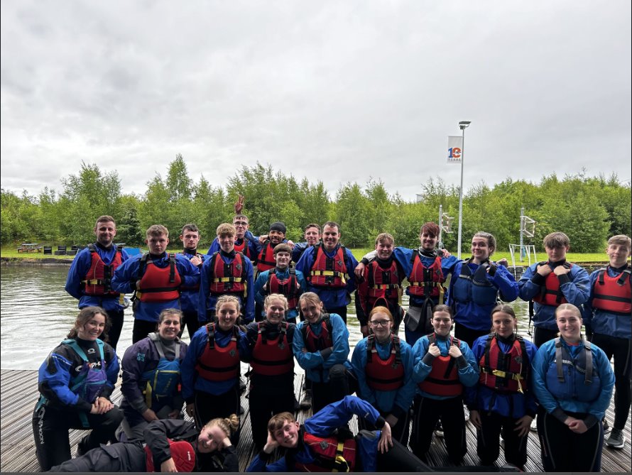  Group of Glasgow Kelvin College students wearing wetsuits and life jackets posing together at Pinkston Watersports Centre after an outdoor activity session.
