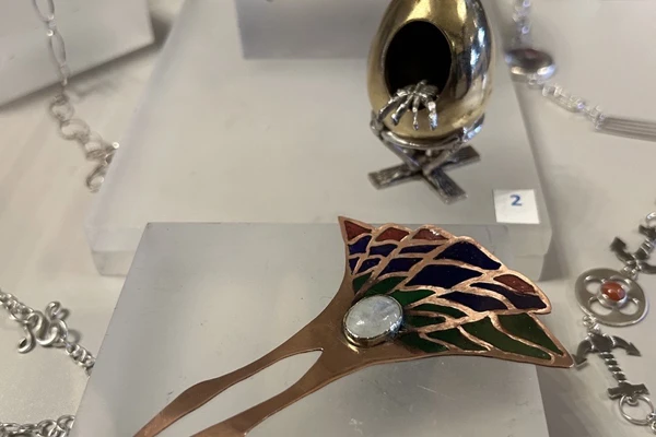 A selection of handcrafted jewellery on display at Craftex 2025, featuring a copper bowl, sculpted egg piece, and an enamelled decorative hairpin. A selection of handcrafted jewellery on display at Craftex 2025, featuring a copper bowl, sculpted egg piece, and an enamelled decorative hairpin.