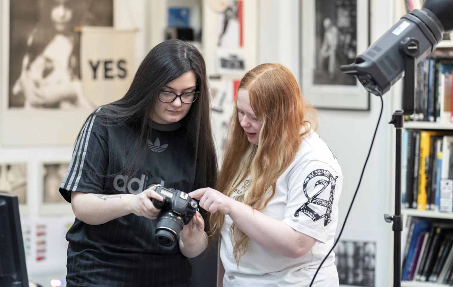 Two students reviewing photos on a DSLR camera in a creative photography studio. Two students reviewing photos on a DSLR camera in a creative photography studio.
