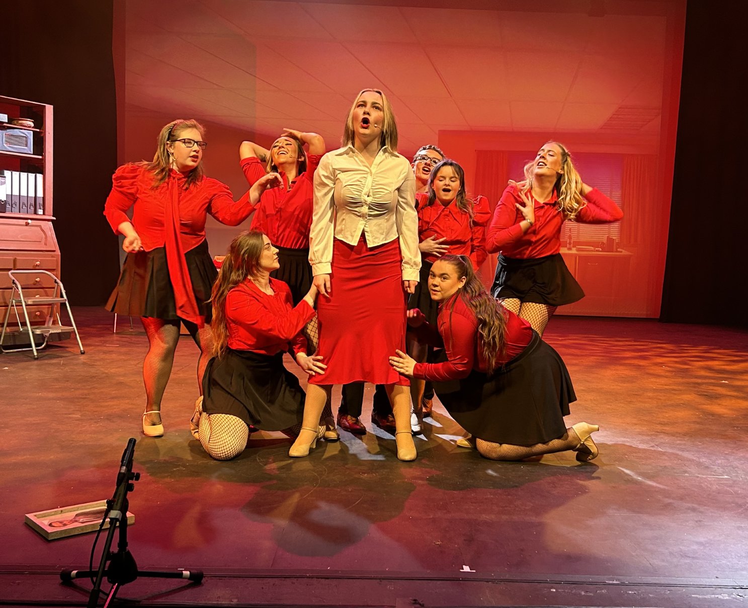 Energetic musical number featuring a group of performers dressed in red, singing passionately on stage.
