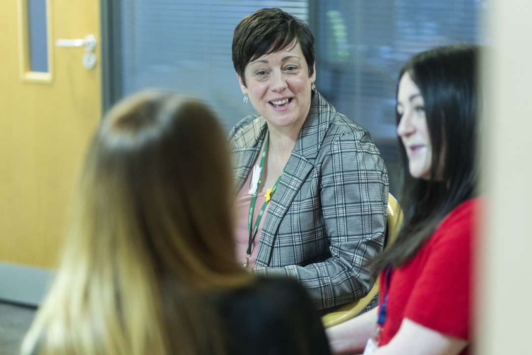 Glasgow Kelvin College staff member in conversation with two colleagues during an informal meeting in an office setting