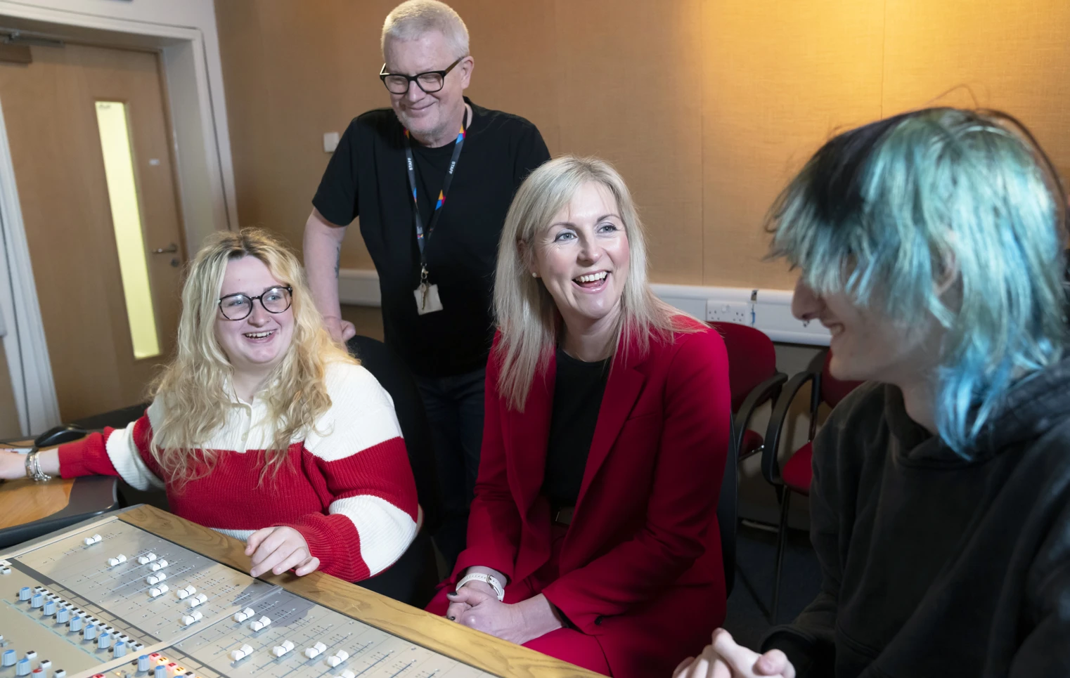 Principal Joanna Campbell chats with students and a staff member in a Glasgow Kelvin College recording studio, all smiling around a sound mixing desk. Principal Joanna Campbell chats with students and a staff member in a Glasgow Kelvin College recording studio, all smiling around a sound mixing desk.