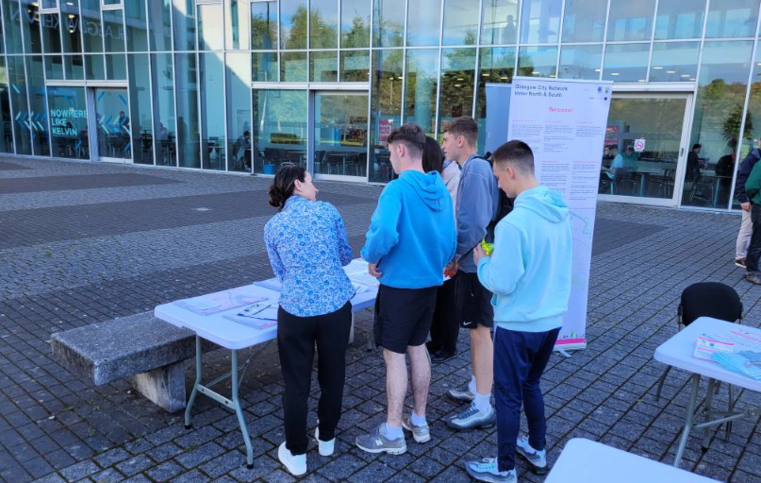 Glasgow Kelvin College students and staff gathered around an information table outside the campus building, exploring new active travel network maps and resources. Glasgow Kelvin College students and staff gathered around an information table outside the campus building, exploring new active travel network maps and resources.