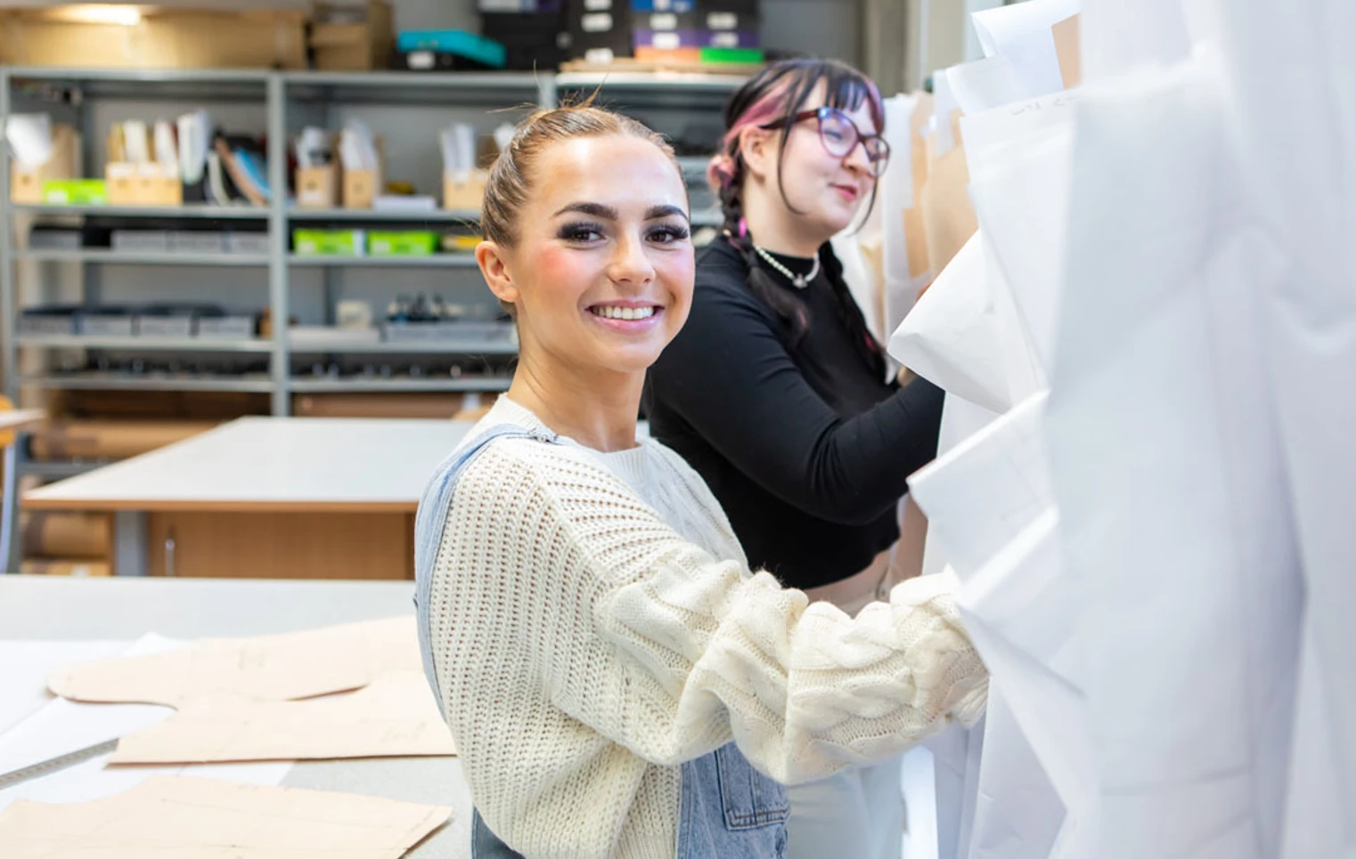 Two fashion students organizing and selecting design patterns in a creative workspace. Two fashion students organizing and selecting design patterns in a creative workspace.