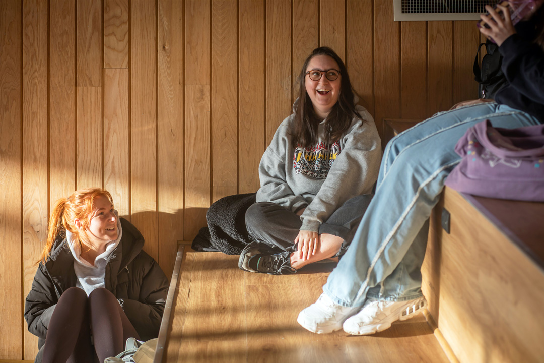 Students relaxing and chatting on wooden tiered seating at the Springburn campus, enjoying the natural light