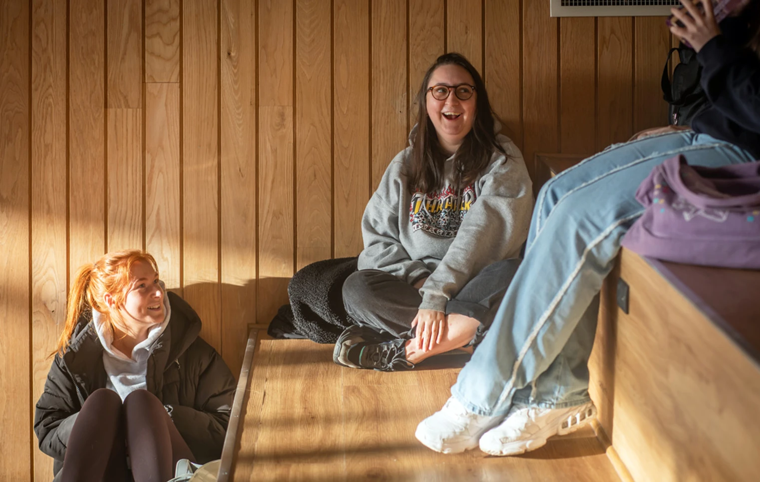 Students relaxing and chatting on wooden tiered seating at the Springburn campus, enjoying the natural light Students relaxing and chatting on wooden tiered seating at the Springburn campus, enjoying the natural light