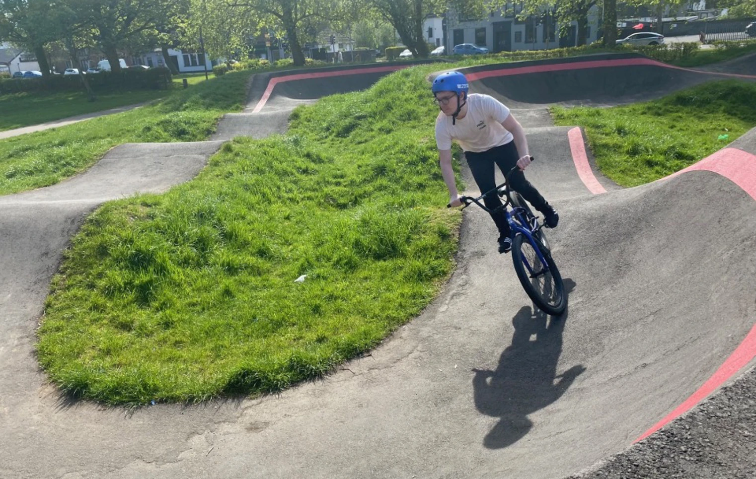 Student riding a BMX bike on an outdoor pump track during a sunny day, part of the Pathways to Employment Skills programme. Student riding a BMX bike on an outdoor pump track during a sunny day, part of the Pathways to Employment Skills programme.