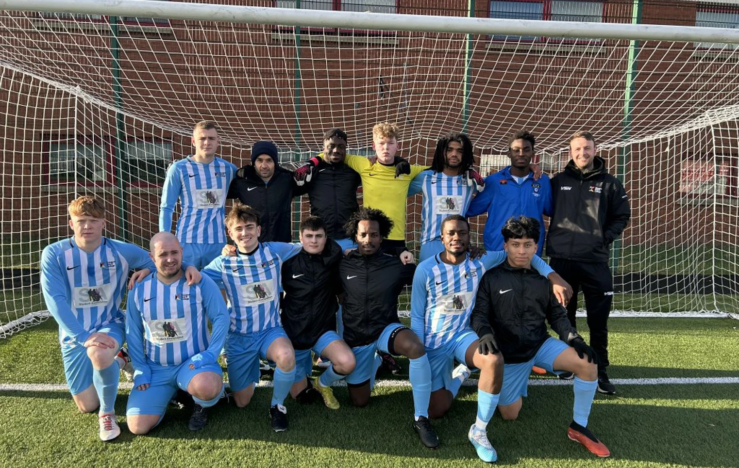Glasgow Kelvin College men's football team posing together in front of a goal on the pitch, wearing blue and white kits. Glasgow Kelvin College men's football team posing together in front of a goal on the pitch, wearing blue and white kits.